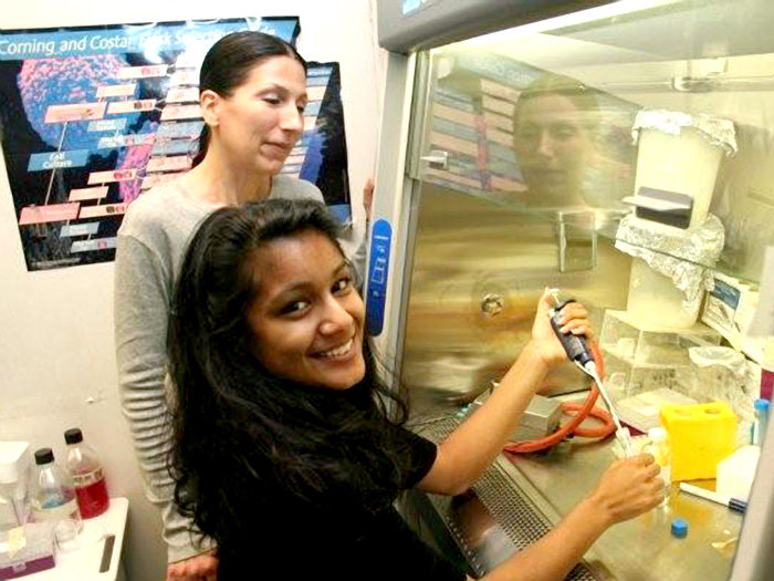 Doctoral student Phyllis Langone (left) and Sneha Banerjee (right) are shown at a biological safety cabinet station.